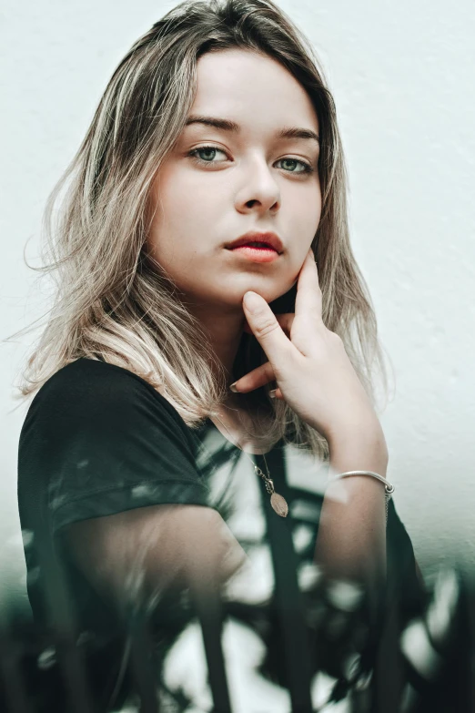 a woman in a black shirt posing for a picture, a picture, inspired by Elsa Bleda, trending on pexels, photorealism, brunette with dyed blonde hair, distant thoughtful look, desaturated, girl silver hair