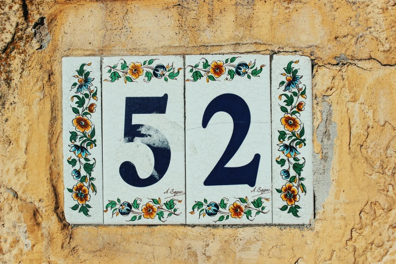 a close up of a sign on a stone wall, a mosaic, by Kristian Zahrtmann, unsplash, numerical, two, seville, 3 2 x 3 2
