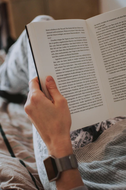 a person reading a book on a bed, over-the-shoulder shot, large)}], image