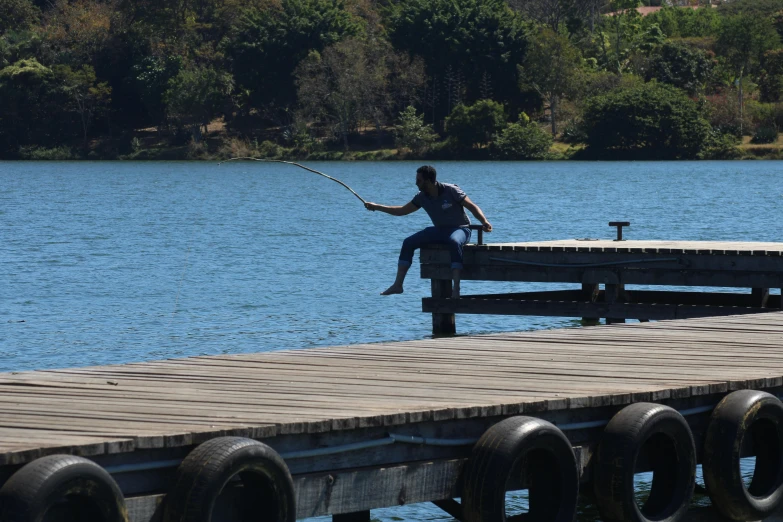 a man sitting on a dock with a fishing rod, by Peter Churcher, pexels contest winner, hurufiyya, jumping, tamborine, low quality footage, no cropping