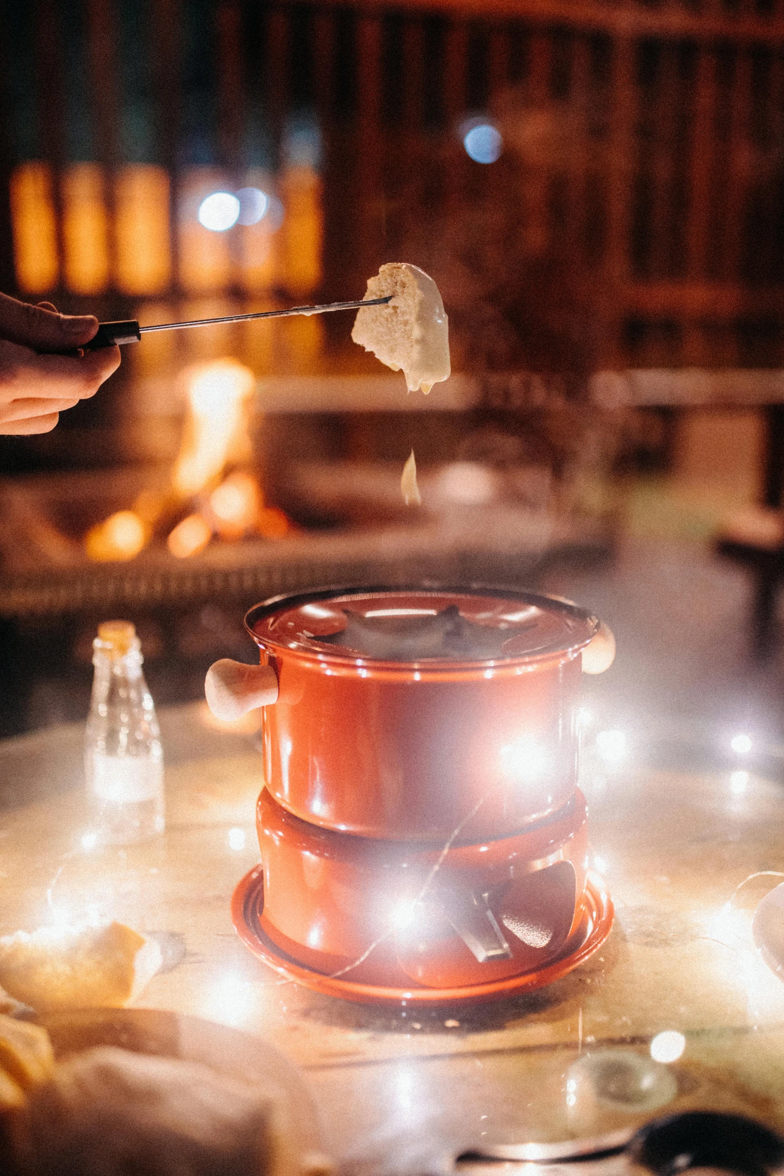 a person roasting marshmallows in front of a fire, bowl filled with food, fairy lights, red smoke coming from lamp, melting cheese