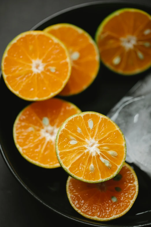 a black plate topped with sliced oranges on top of a table, lime, 6 pack, multiple stories, medium format