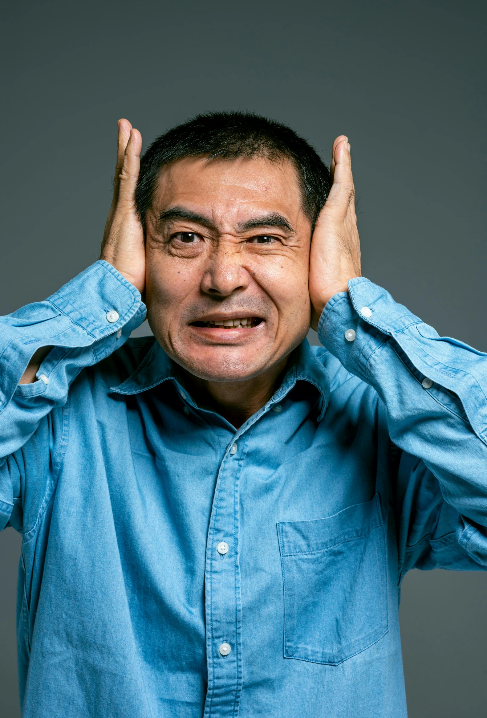 a man covering his ears with his hands, by Murakami, pexels, mingei, an film still of mr bean, plain background, ernie chan, noise effect