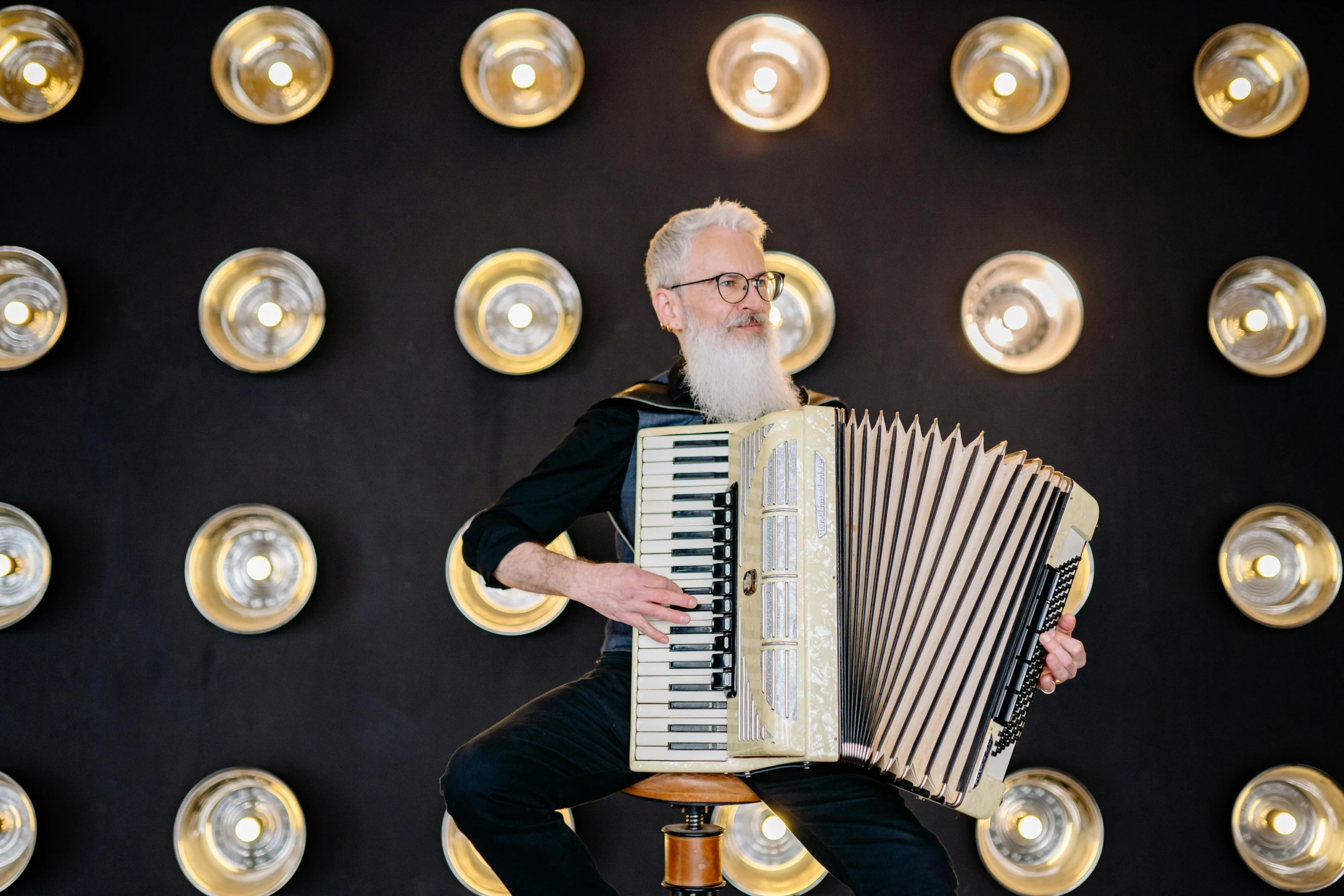 a man sitting on a stool playing an accordion, by Julia Pishtar, silver hair and beard, backdrop, lachlan bailey, rectangle