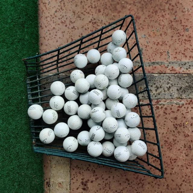 a basket full of golf balls on the ground, by Tom Wänerstrand, unsplash, photorealism, wide high angle view, “ iron bark, 1 6 x 1 6, indoor shot