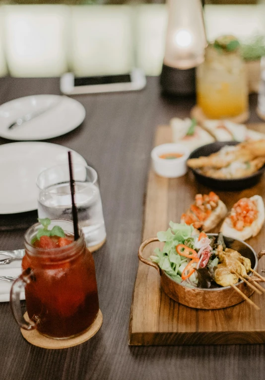 a wooden table topped with plates of food, unsplash, drinks, square, low detail, resort