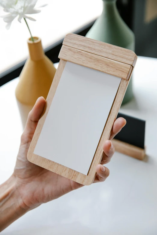 a person holding up a wooden picture frame, a picture, notes, top lid, sleek design, holds playing cards