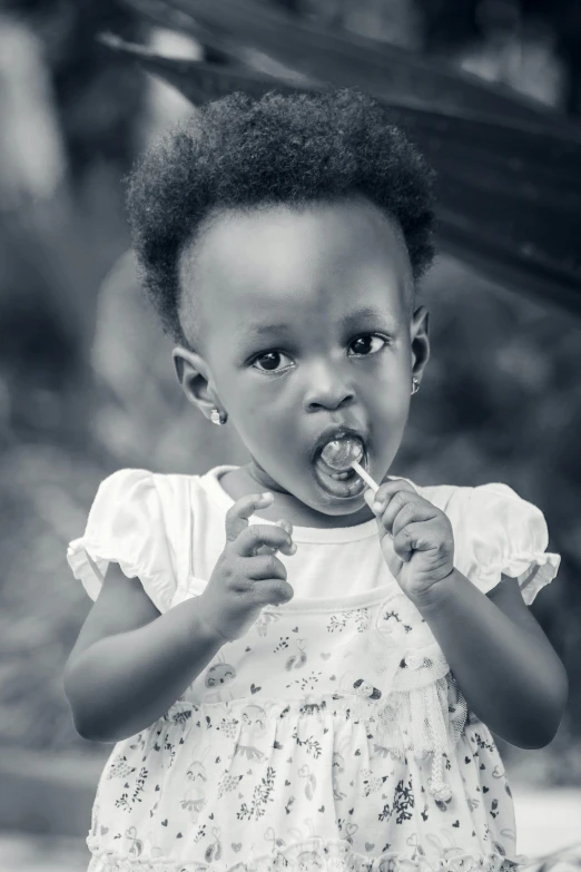 a black and white photo of a little girl brushing her teeth, a black and white photo, by Chinwe Chukwuogo-Roy, pexels contest winner, handsome girl, lollipop, 2 years old, complex background