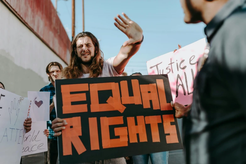 a group of people holding signs in front of a building, trending on pexels, feminist art, brught tones, man standing, justice, 2045