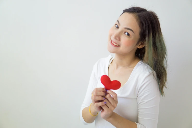 a woman holding a red heart in her hands, inspired by Ni Duan, pexels contest winner, hurufiyya, avatar image, cute young woman, small in size, product shot