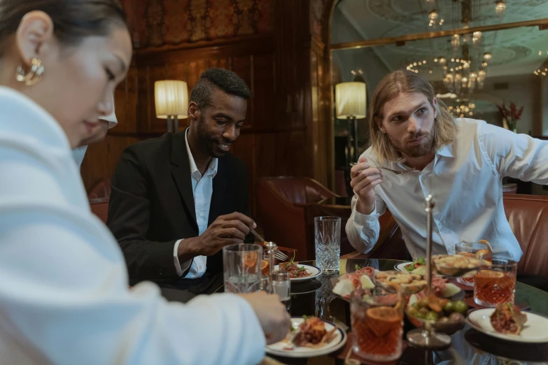 a group of people sitting at a table with plates of food, gentleman, profile image, still cinematic, about to consume you