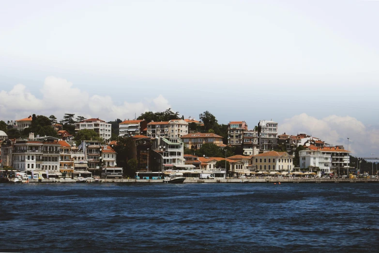 a large body of water filled with lots of buildings, a colorized photo, by Emma Andijewska, pexels contest winner, the fall of constantinople, coastline, full body image, photo taken from a boat