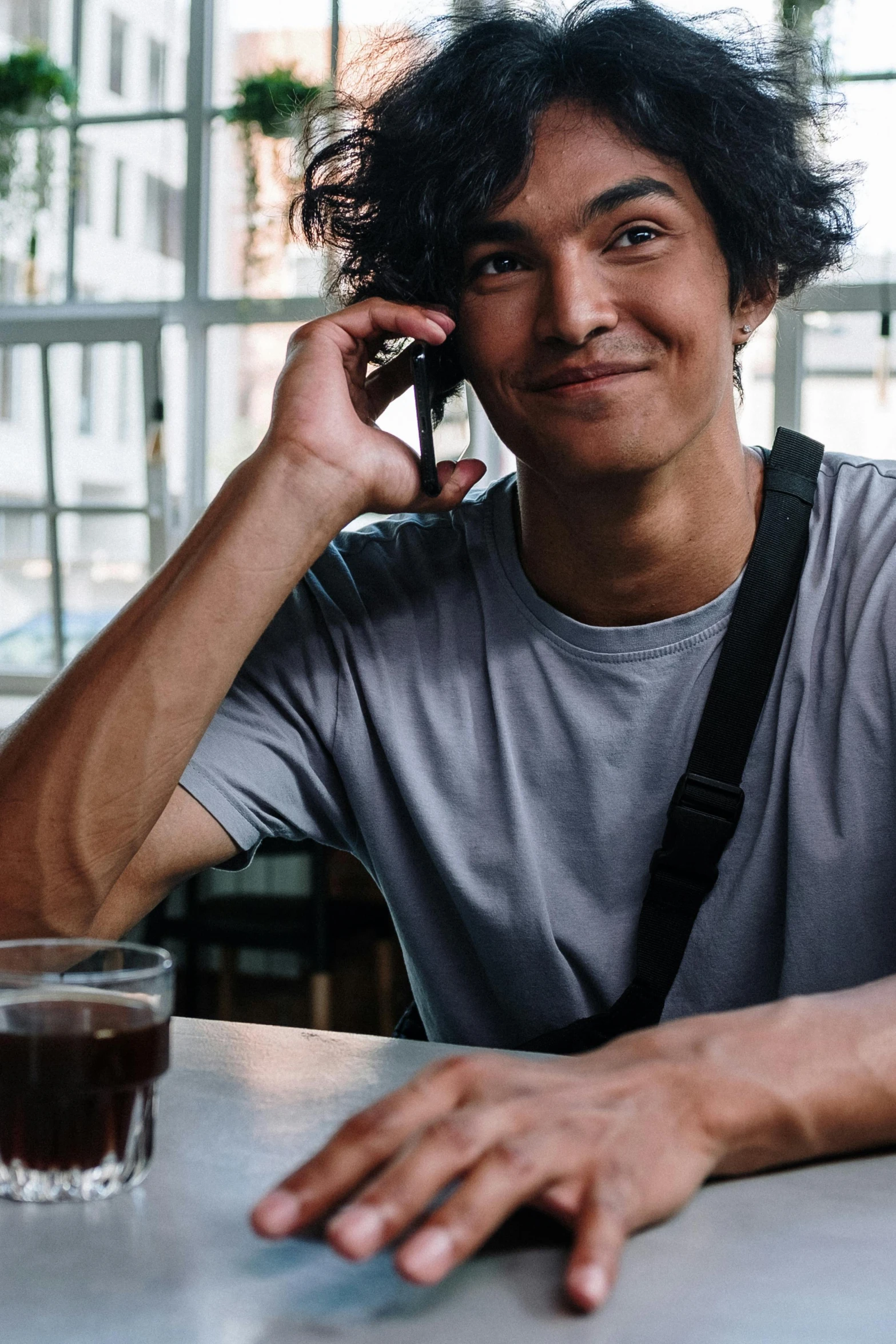 a man sitting at a table talking on a cell phone, pexels, renaissance, curly and short top hair, cold brew coffee ), non binary model, hispanic