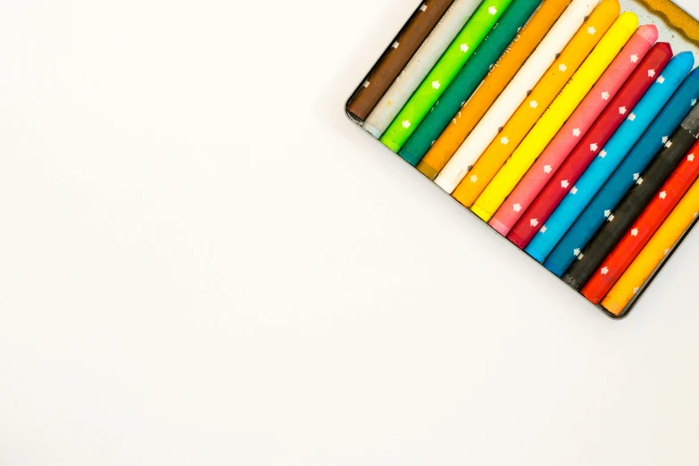 a box of colored pencils sitting on top of a table, a minimalist painting, on a white background, coloured with lots of colour, !pencil, on a canva