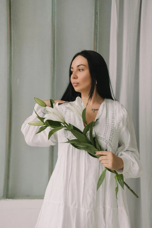 a woman in a white dress holding a bunch of flowers, inspired by Marina Abramović, pexels contest winner, art nouveau, wearing a linen shirt, lily, promo image, willow plant