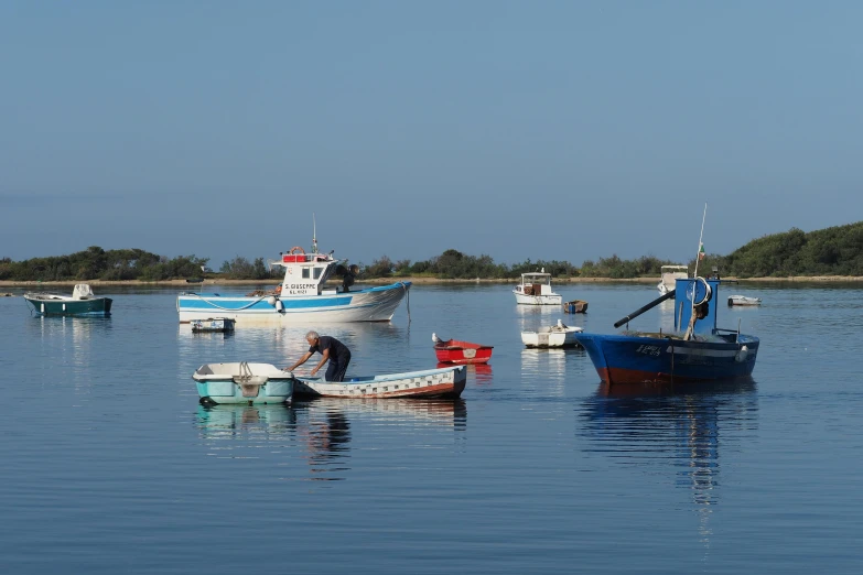 a number of boats in a body of water, a photo, by Bertram Brooker, pexels contest winner, hurufiyya, apulia, older male, blue reflections, thumbnail