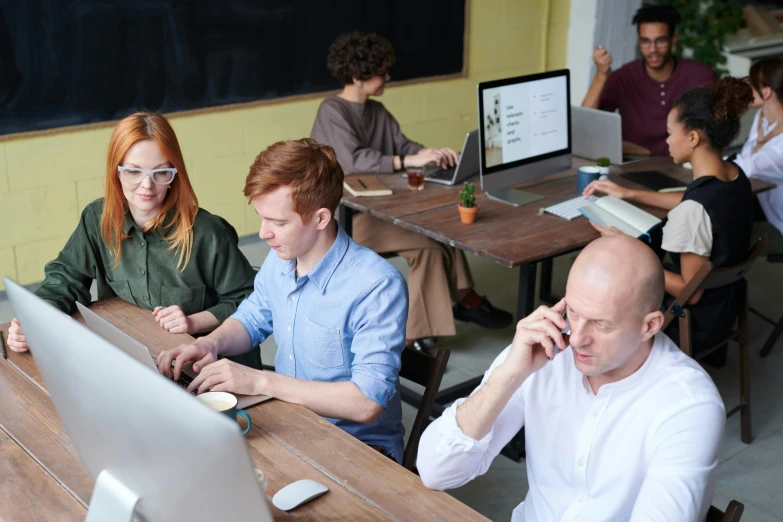 a group of people sitting at a table working on laptops, by Adam Marczyński, trending on pexels, hr ginger, sitting at desk at keyboard, 9 9 designs, 15081959 21121991 01012000 4k