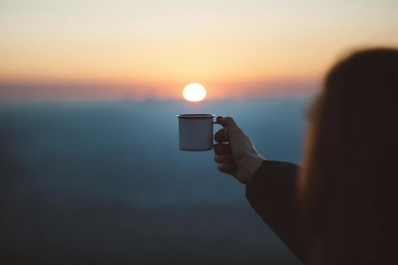 a person holding a cup with the sun setting in the background, pexels contest winner, morning haze, instagram post, frank moth, :: morning