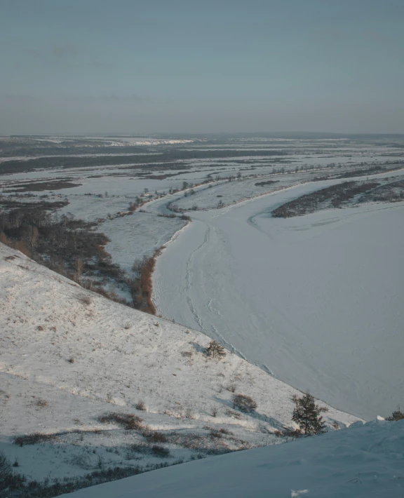 a man riding skis down a snow covered slope, wide river and lake, west slav features, snowy field, image