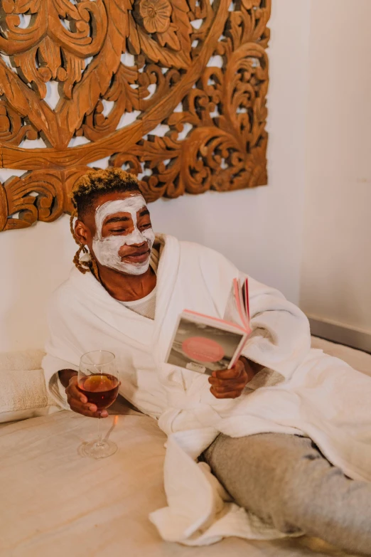 a man sitting on the floor reading a book, an album cover, by Cosmo Alexander, pexels contest winner, happening, face mask, spa, themed after wine, brown skin