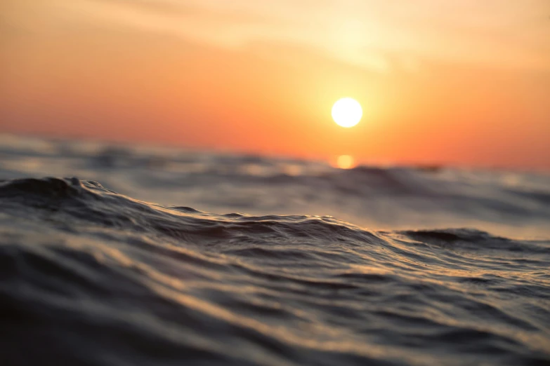 the sun is setting over a body of water, a picture, unsplash, romanticism, wavy water, close-up photograph, horizon line focus, subsurface