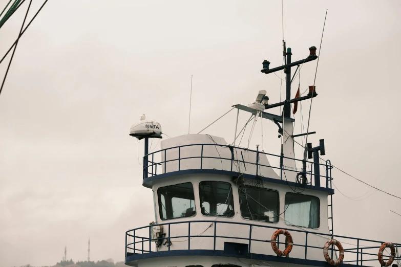 a large white and blue boat on a body of water, a portrait, unsplash, hurufiyya, gray sky, antenna, maintenance photo