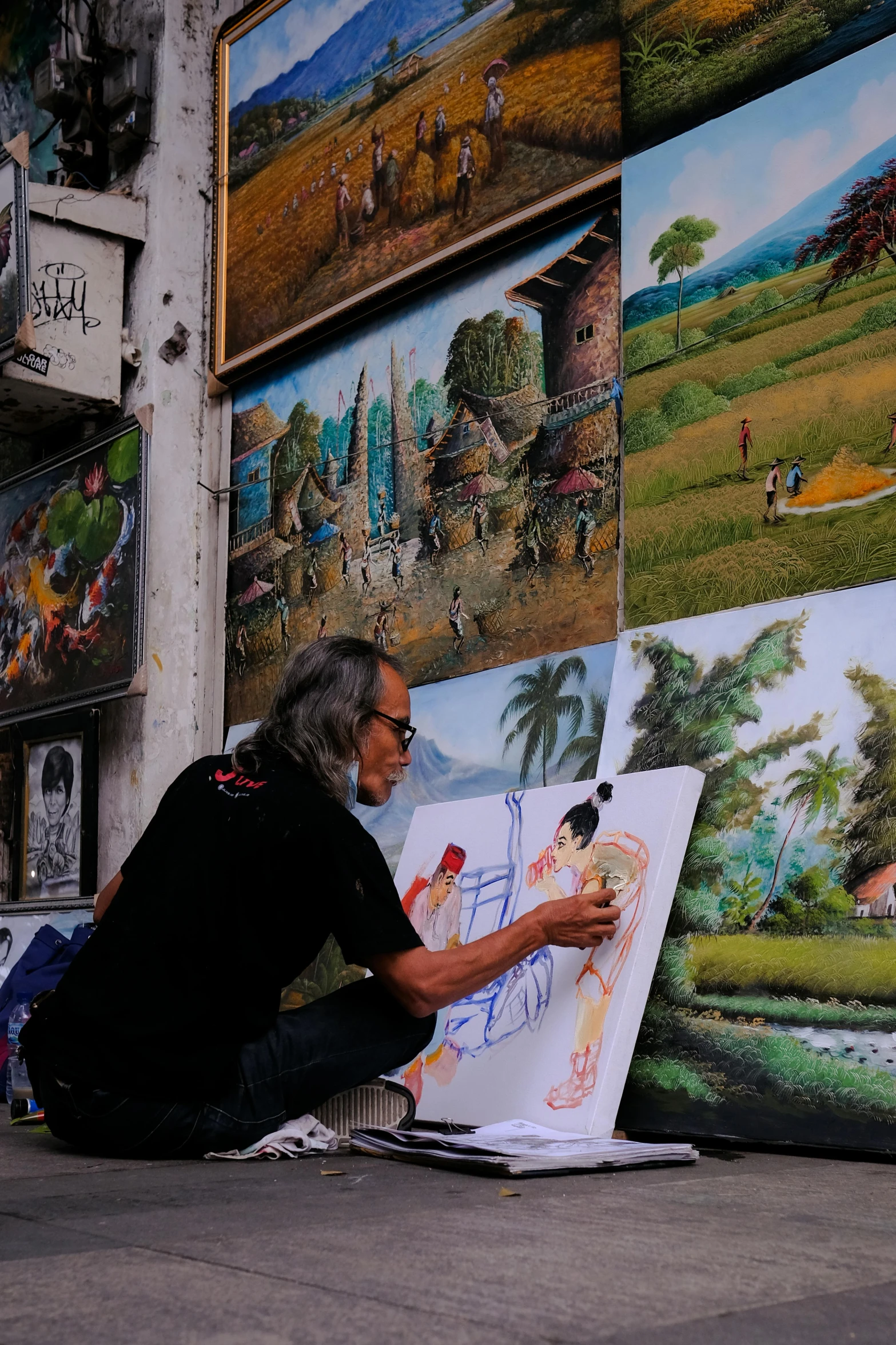 a man sitting on the ground working on a painting, inspired by Bhupen Khakhar, pexels contest winner, street art, bali, foreground background, crafts and souvenirs, michael kaluta