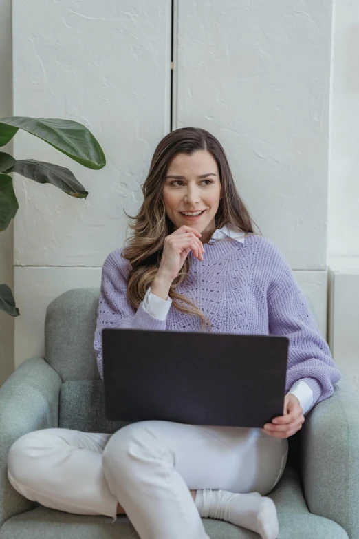 a woman sitting in a chair with a laptop, a portrait, trending on pexels, white and purple, wearing casual sweater, pokimane, wearing elegant casual clothes