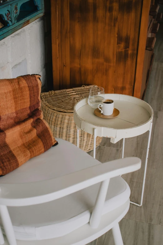 a white chair sitting next to a table with a cup of coffee on it, inspired by Riad Beyrouti, cottagecore, rust, prop, round-cropped