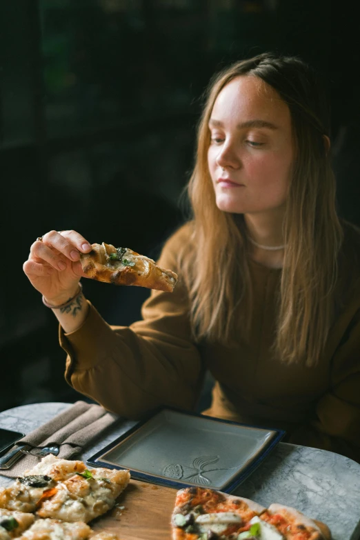 a woman sitting at a table eating a slice of pizza, inspired by Elsa Bleda, pexels contest winner, renaissance, sydney sweeney, restaurant, bread, college