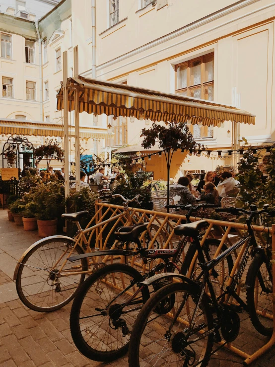 a group of bicycles parked next to each other on a sidewalk, by Emma Andijewska, pexels contest winner, art nouveau, yellow awning, moscow, un restaurant avec une terrasse, gif