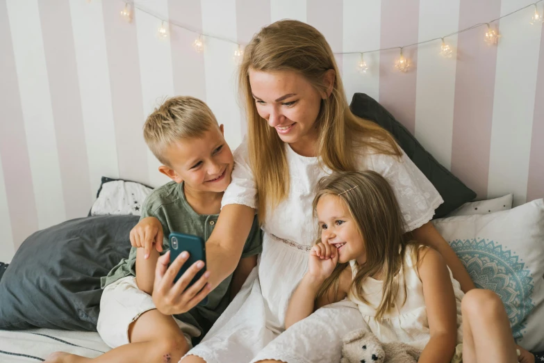 a woman and two children sitting on a bed, pexels contest winner, she is holding a smartphone, 15081959 21121991 01012000 4k, a blond, 1x