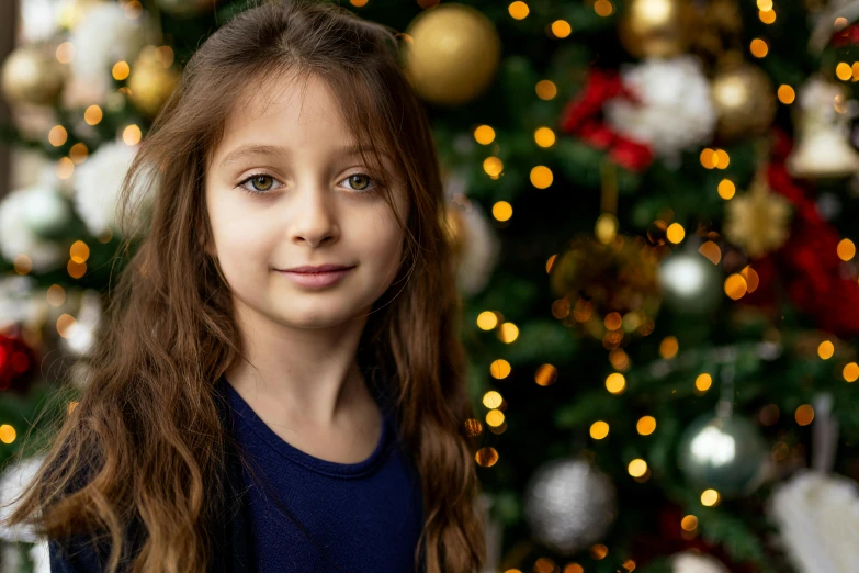 a little girl standing in front of a christmas tree, a portrait, pexels contest winner, avatar image, girl with brown hair, close - up photo, handsome girl