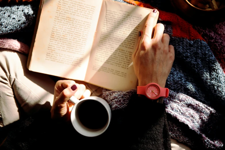 a person reading a book while holding a cup of coffee, by Romain brook, pexels contest winner, pink and orange, wears a watch, 15081959 21121991 01012000 4k, winter sun