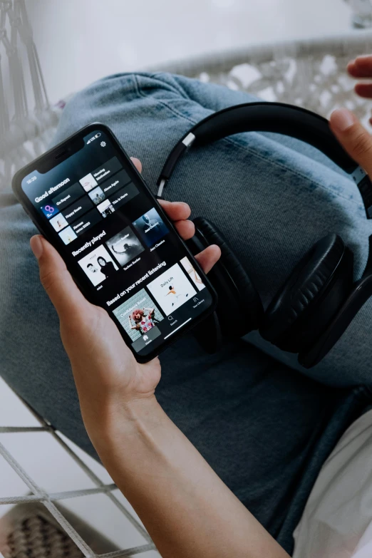 a person holding a cell phone and wearing headphones, curated collections, deep black, thumbnail, home