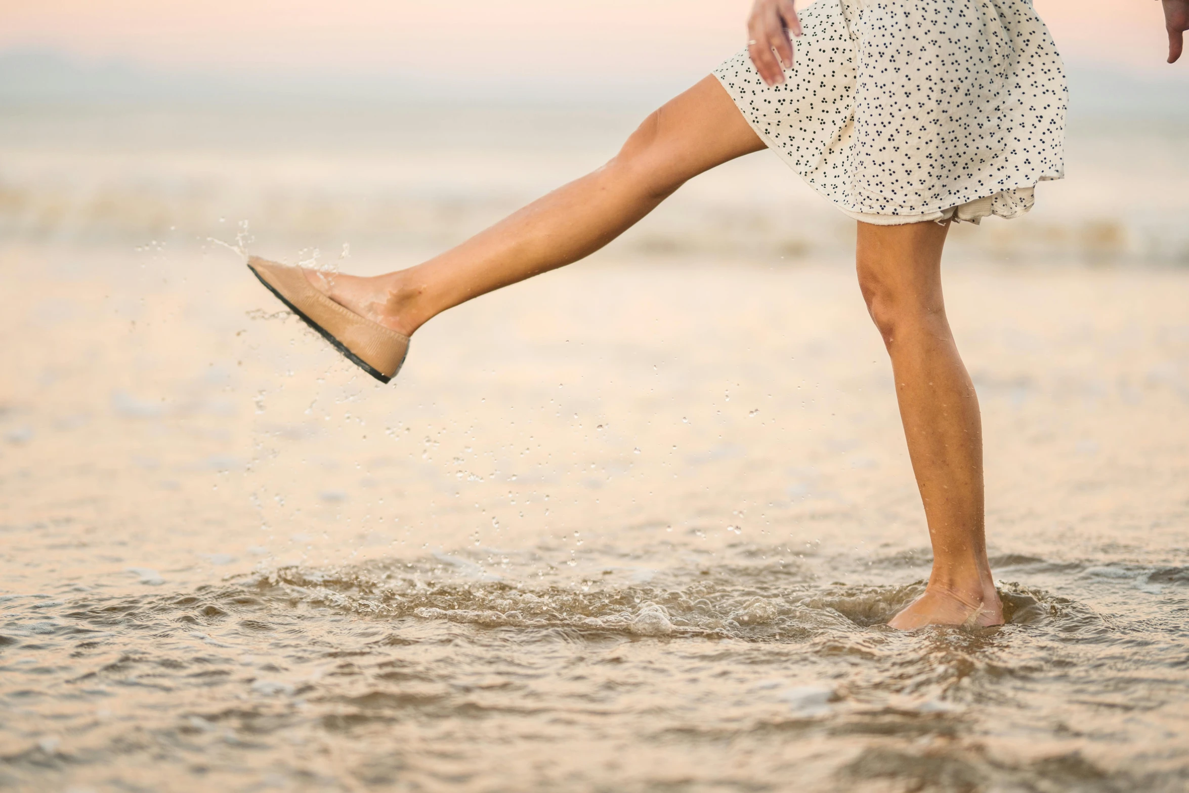 a woman standing in the water with her legs in the air, by Arabella Rankin, unsplash, light tan, wearing in a summer dress, 15081959 21121991 01012000 4k, shows a leg