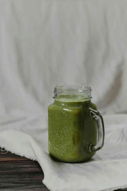 a green smoothie sitting on top of a wooden table, a picture, unsplash, on grey background, gif, full frame image, moroccan