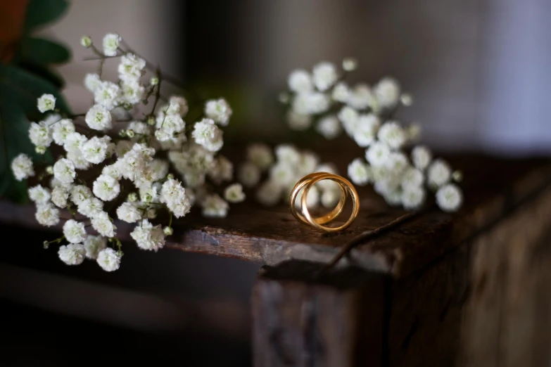 a couple of wedding rings sitting on top of a wooden table, caroline foster, gypsophila, gold, multiple stories