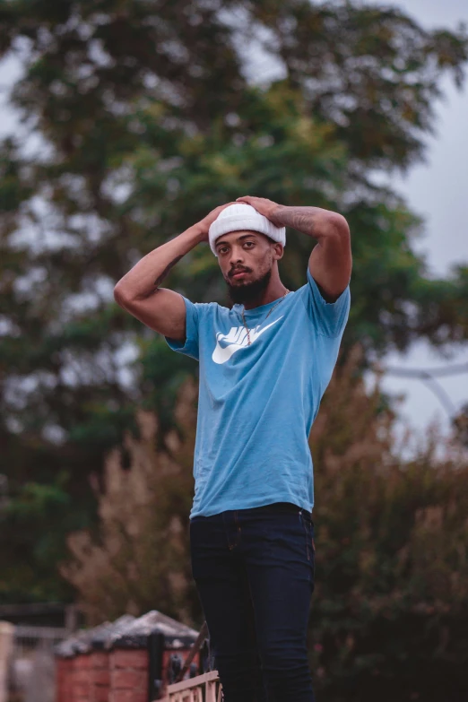 a man in a blue shirt standing on a skateboard, pexels contest winner, renaissance, wears a destroyed hat, depressed dramatic bicep pose, trending on r/streetwear, lake blue