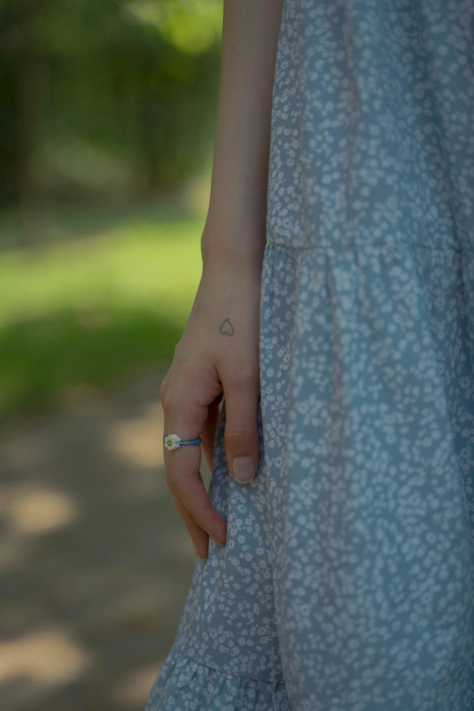 a close up of a person with a ring on their finger, a tattoo, under the soft shadow of a tree, wearing in a summer dress, cinematic shot ar 9:16 -n 6 -g, low quality photo