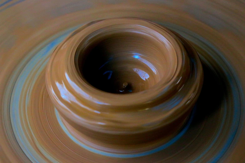 a close up of a bowl on a potter's wheel, by Doug Ohlson, process art, caramel, full dynamic colour, vinyl, slow motion