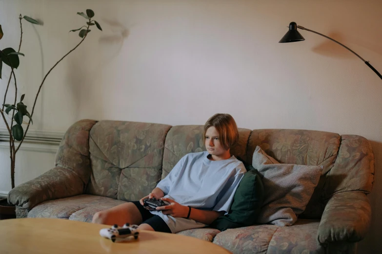 a woman sitting on a couch playing a video game, inspired by Elsa Bleda, pexels, realism, teenage boy, low quality photo, landscape shot, 90s photo