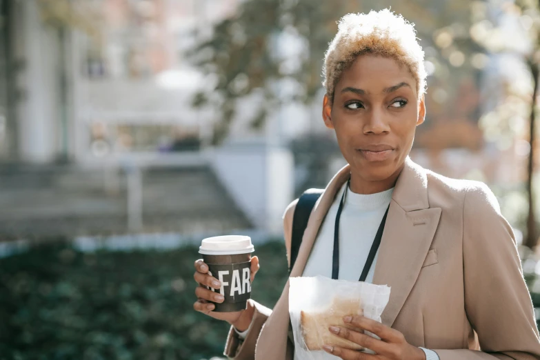 a woman holding a cup of coffee and a paper bag, trending on unsplash, afrofuturism, short blonde afro, concerned, fall season, fair skinned