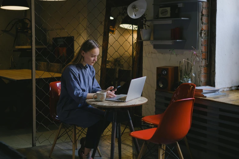 a woman sitting at a table with a laptop, pexels contest winner, happening, sitting on chair, low quality photo, multiple stories, early evening