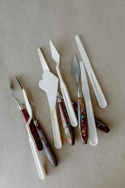 a number of forks and knives on a table, a still life, inspired by Stanley Spencer, instagram, process art, paper marbling, brown resin, on a pale background, surgical equipment