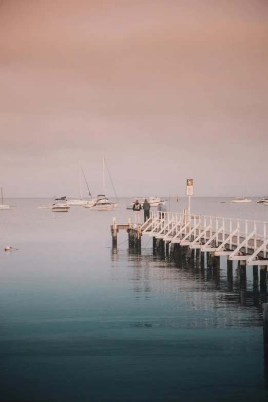 a pier in the middle of a body of water, boats in the water, soft morning lighting, lachlan bailey, calmly conversing 8k