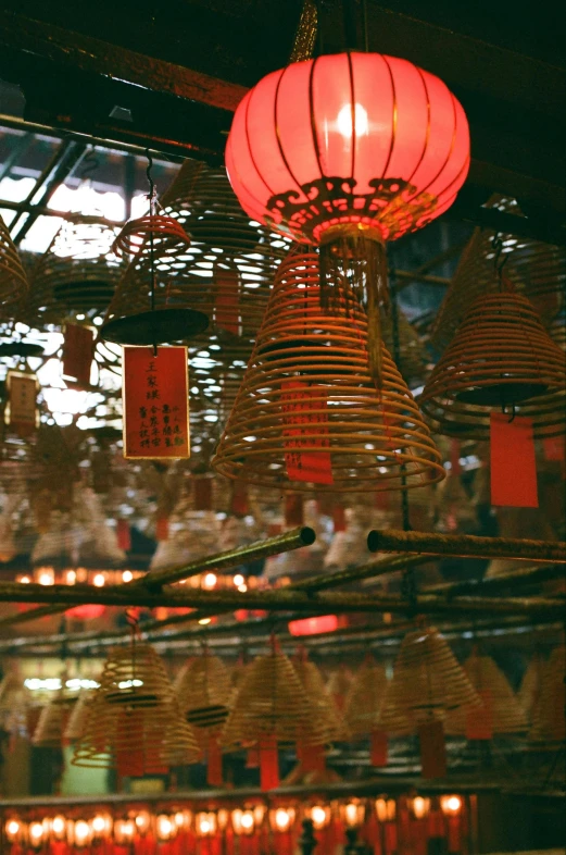 a bunch of red lanterns hanging from a ceiling, in 2 0 0 2, incense, a still of kowloon, golden light