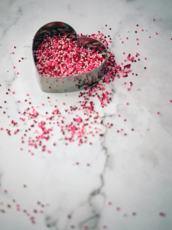 a heart shaped cookie cutter filled with pink sprinkles, by Anna Findlay, pexels, cranberry statue, gif, boke, unedited