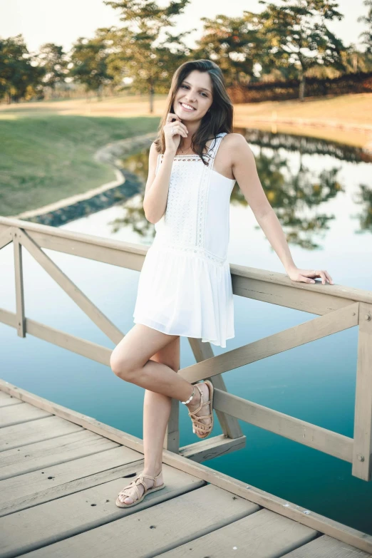 a woman standing on a bridge talking on a cell phone, by Robbie Trevino, renaissance, wearing a cute white dress, casual pose, college, pr shoot