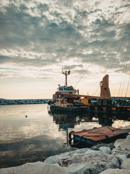 a boat sitting on top of a body of water, docked at harbor, 🚿🗝📝, with dramatic sky, thumbnail